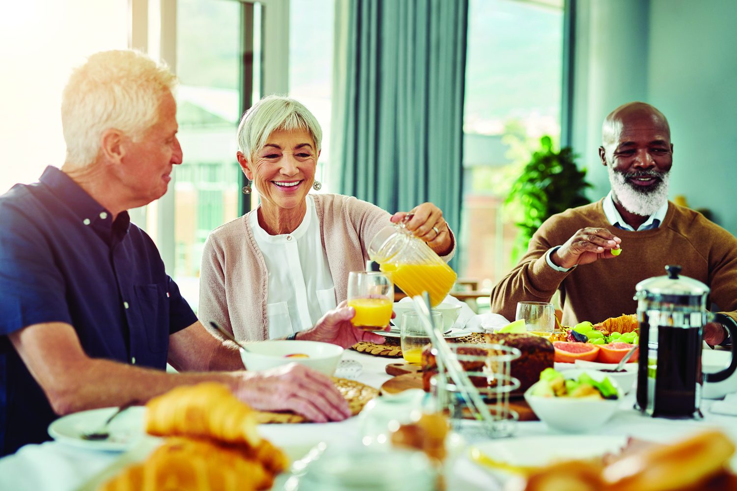Shot of a cheerful group of senior people talking and enjoying breakfast together at home