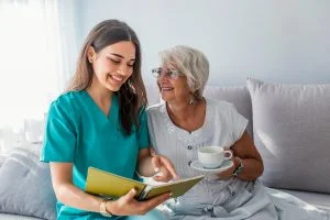 Caregiver Reads with Senior Woman on Couch_Memory Care Boca Raton