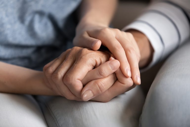 When is it Time to Move from Boca Raton Assisted Living to Memory Care? Closeup of Senior and Adult Child Holding Hands_Boca Raton Assisted Living