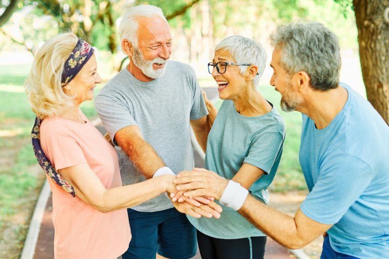 How to Build Your Circle of Friends in Boca Raton Senior Living Group of Laughing Seniors Outside with Their Hands Together_Boca Raton Senior Living