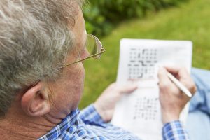 Enhance Life with New Year's Resolutions for Healthy Aging Senior Man Completing Crossword Puzzle_Retirement Community in Boca Raton