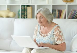 Senior Woman on Couch Looking at Laptop_Boca Raton Senior Living