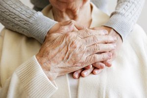 Assisted Living vs. Memory Care: What Are the Differences? Caregiver taking the hand of an older adult.