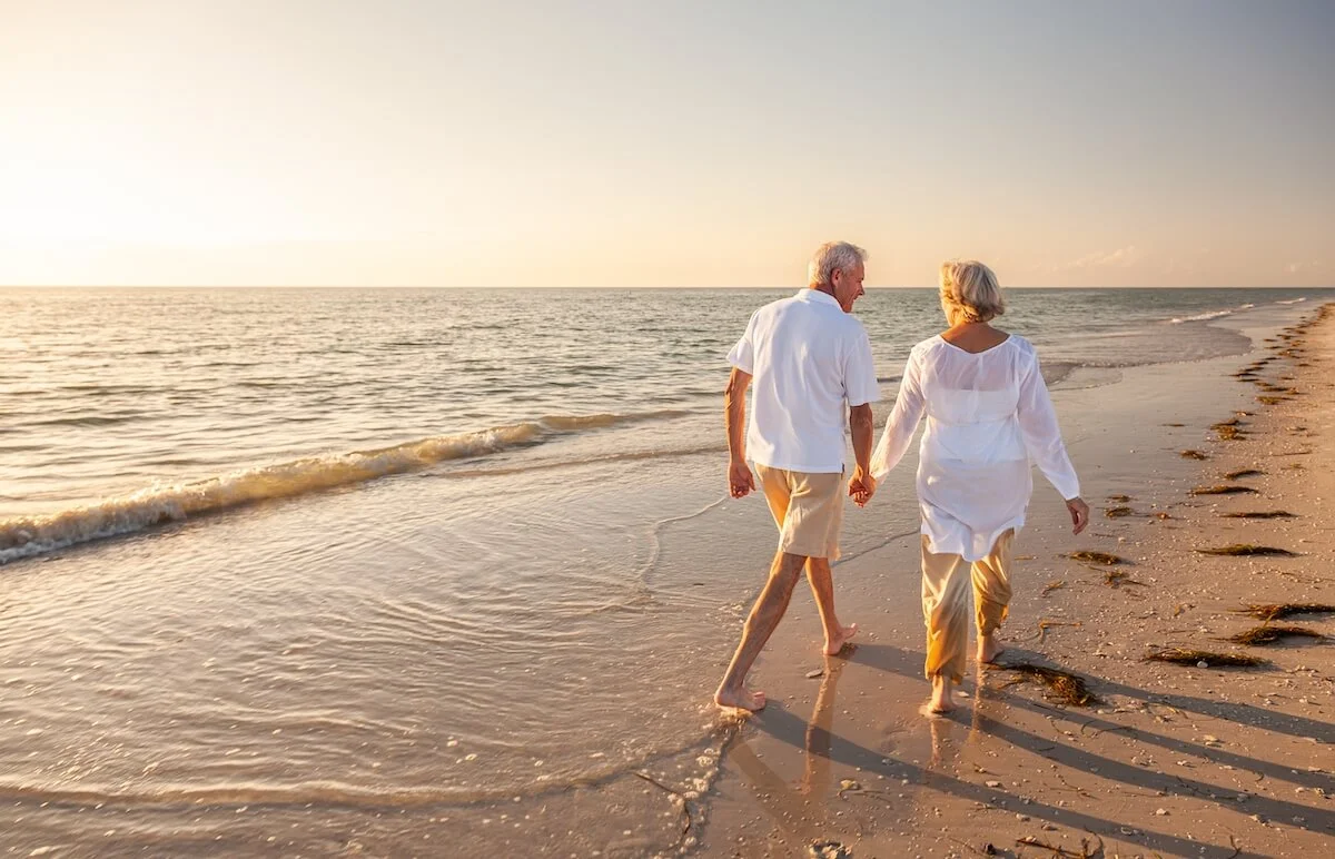 Couple of seniors holding hands and walking on the beach