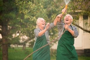 Couple of happy seniors watering their plants together