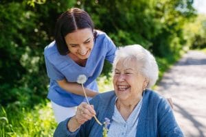 Caregiver with an older woman holding a flower