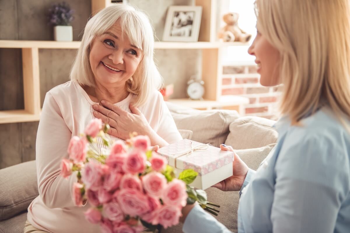 Smiling elderly mom receiving flowers on Mothers Day