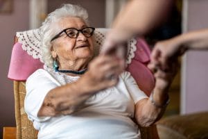 Older woman with dementia holding hands with a relative