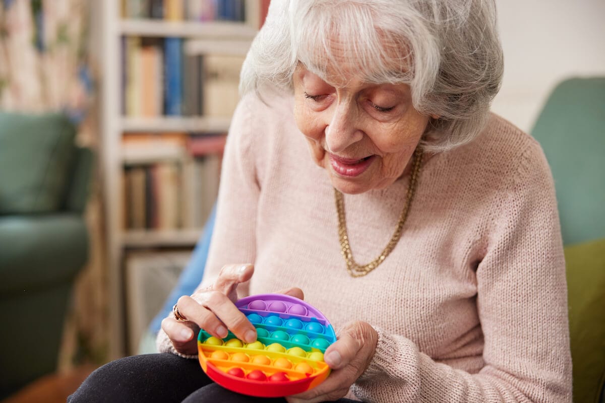 Older woman using a colorful toy as a resource for dementia