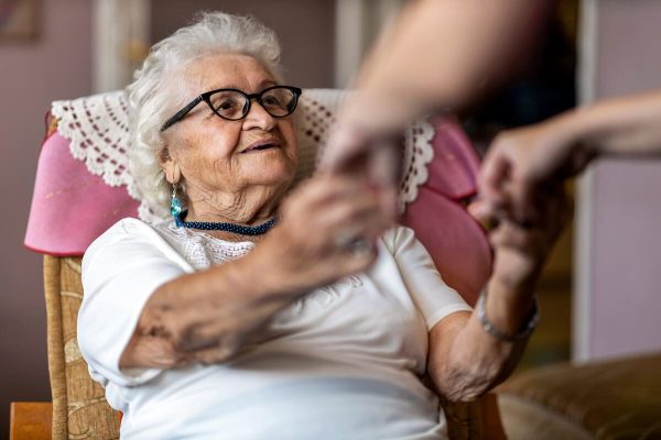 Older woman with dementia holding hands with a relative